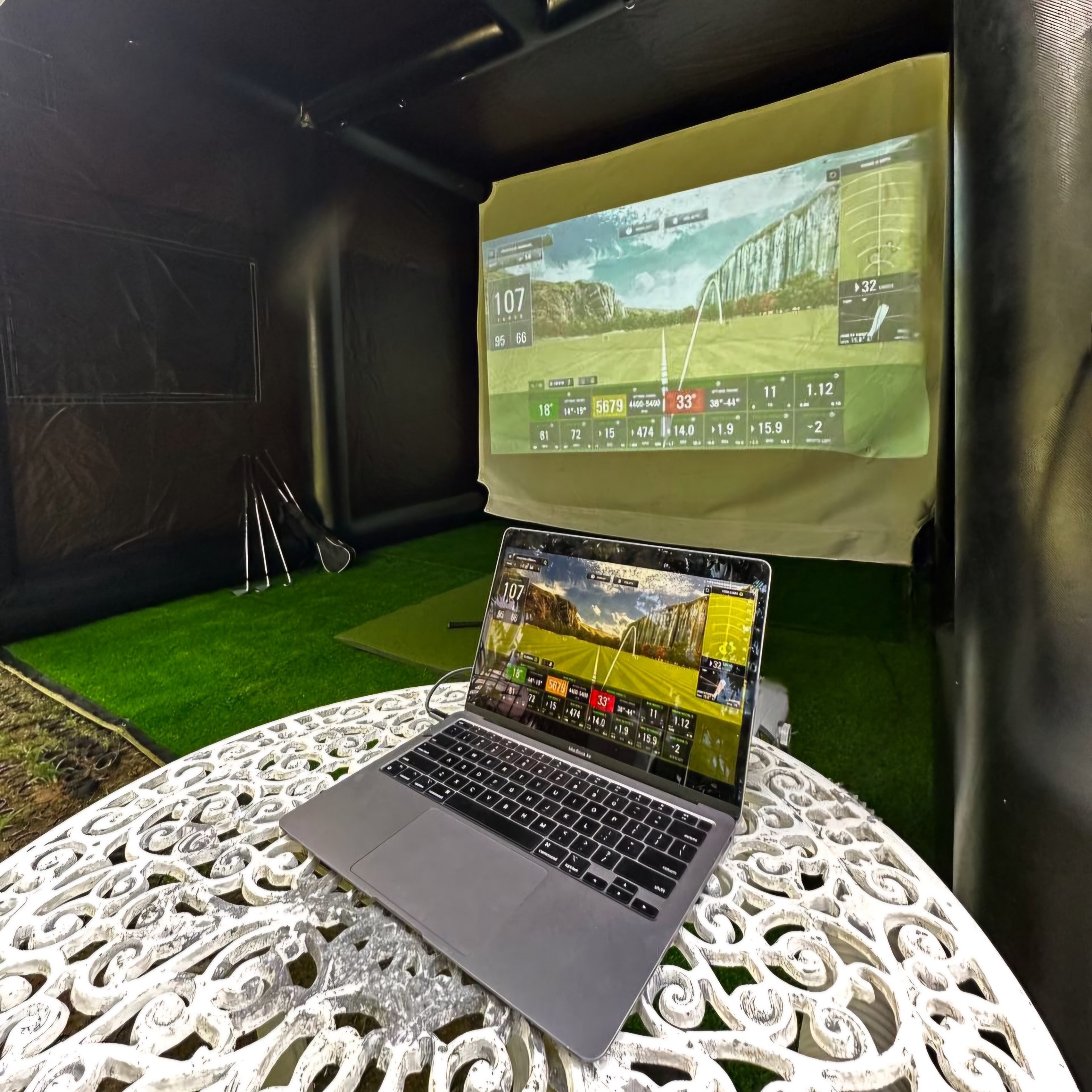 Golf Anywhere night setup — laptop and simulator screen glowing inside the tent